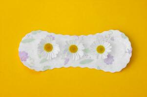 Menstrual pads with chamomiles on yellow background. photo