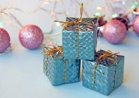 Christmas decoration for the Christmas tree in the form of small shiny gifts and balls on a blue background. photo