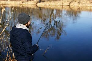 Fishing rod in the hands of a fisherman on the lake. photo