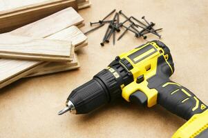 The yellow-black screwdriver on wood background, screws. photo