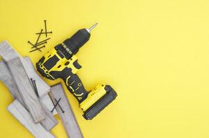 The yellow-black screwdriver on a yellow background, screws, a set of bits. photo