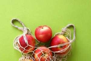 Red apple and string bag on a bright green background. photo