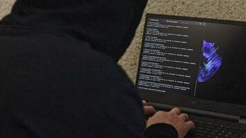 homme regardé comme pirate dans une capuche séance dans le de face de ordinateur portable, l'écriture une code, La technologie video