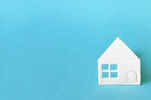 Little house of white paper on light blue background. photo