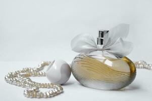 Perfume bottle with pearl on light background. photo