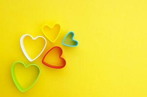 Plastic molds of multi colors for making cookies in the shape of a hearts on a yellow background. photo