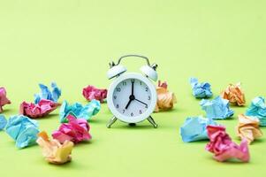 Vintage white alarm clock on a background of crumpled multicolored stickers. photo