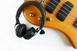 Portable black headphones and bass guitar on white background. photo