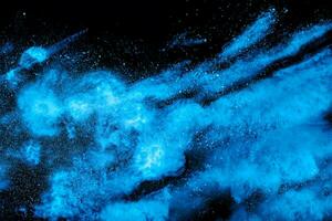 Blue powder explode cloud on black background. Launched blue dust particles splash on  background. photo