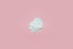 White face powder on pink background photo