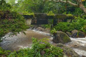 Old bridge over a rocky stream on a nature trail photo