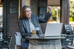 Cheerful woman rejoicing over successful bet holding credit card photo