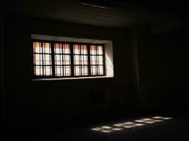 Rectangular window with double frame and shining light leaving a reflection of it on the floor, photography taken from a dark room bottom up view photo