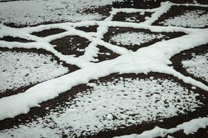 Naturally created geometrical snow patterns on dark asphalt road photo