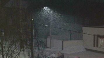 langzaam beweging beeldmateriaal van de sneeuw vallend Bij nacht Aan de straat. seizoen video