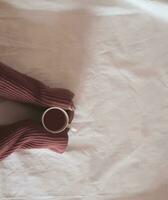 hand holding tea cup on table, cozy hugge concept. Pastel colors, warm sweater, vintage style. High quality photo. photo