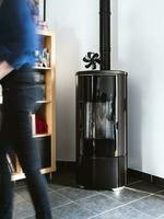 Woman walking near pellet stove in living room with library photo
