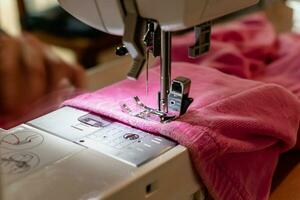 Man using a sewing machine with a pink garment, for repair work, customization, creation, upcycling photo