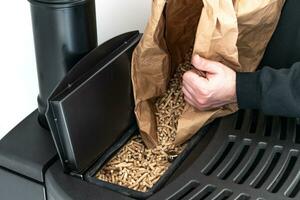 Man loading pellet stove with granule bag photo