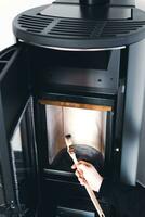 Man cleaning pellet stove with brush photo