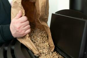 Man loading pellet stove with granule bag photo