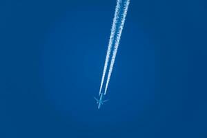 Plane and its condensation trail, cloud forming at the back of a plane, perfectly blue sky photo