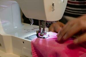 hombre utilizando un de coser máquina con un rosado prenda, para reparar trabajar, personalización, creación, reciclado foto