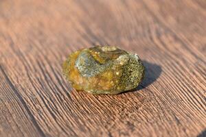 Stone of gallbladder. The result of gallstones. A calculus of dissimilar composition on a wooden background. photo