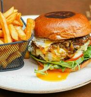 Full rustic beef burger with fries and fried egg photo