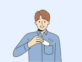 Man takes out business card from pocket to exchange contacts with potential partner or buyer and looks into camera with smile. Business guy in blue shirt wants to share contacts with new acquaintances vector