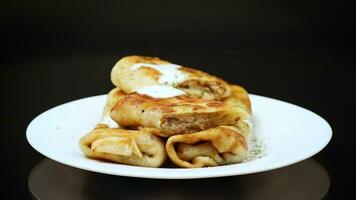 magro fritte Pancakes con carne Riempimento nel un' piatto con acida crema e spezie. video