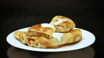 Thin fried pancakes with meat filling in a plate with sour cream and spices. video