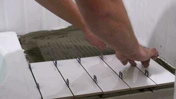 The hands of the tiler are laying white ceramic tile on the wall video