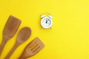 A set of bamboo dishes and a white vintage clock on a bright yellow background. photo