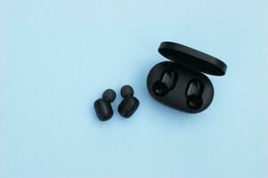 Wireless headphones or earbuds with charging case on bright blue background. photo