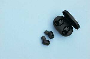 Wireless headphones or earbuds with charging case on bright blue background. photo