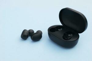 Wireless headphones or earbuds with charging case on bright blue background. photo