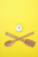 A set of bamboo dishes and a white vintage clock on a bright yellow background. photo