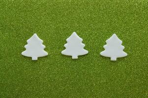 White carved christmas trees of mastic on green background. photo