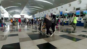 multitud de turistas con equipaje en el kualanamu aeropuerto Terminal. aerolínea pasajeros en un internacional aeropuerto terminal video