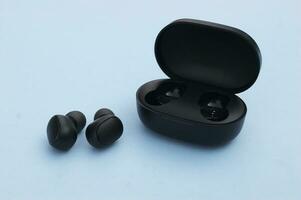 Wireless headphones or earbuds with charging case on bright blue background. photo