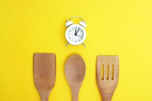 A set of bamboo dishes and a white vintage clock on a bright yellow background. photo