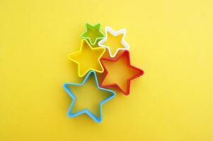 Plastic molds of multi colors for making cookies in the shape of a star on a yellow background. photo