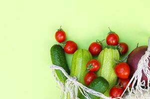 Ripe juicy red tomatoes, green cucumbers and zucchini in a string bag. photo