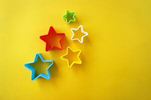 Plastic molds of multi colors for making cookies in the shape of a star on a yellow background. photo