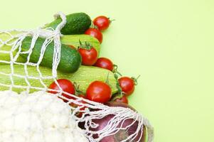 Ripe juicy red tomatoes, green cucumbers, zucchini and cauliflower in a string bag photo