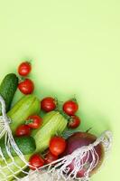 Ripe juicy red tomatoes, green cucumbers, zucchini and cauliflower in a string bag photo