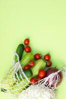 maduro jugoso rojo Tomates, verde pepinos, calabacín y coliflor en un cuerda bolso foto