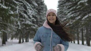 content fille court par le hiver forêt dans une bien ambiance et sourit. lent mouvement HD video