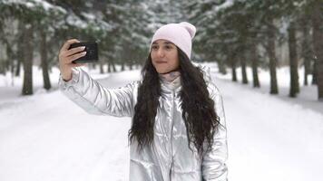 schön Mädchen macht Selfie mit ein Smartphone während Stehen im das Winter Wald video